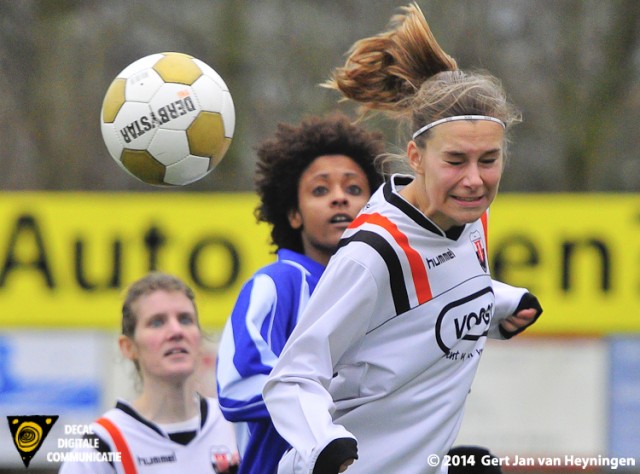 Lisa Stigter van Jodan Boys kopt de bal net weg voor de inkomende Elsa Pinto van SVS. Op de achtergrond kijkt Toos den Oudsten goedkeurend toe.